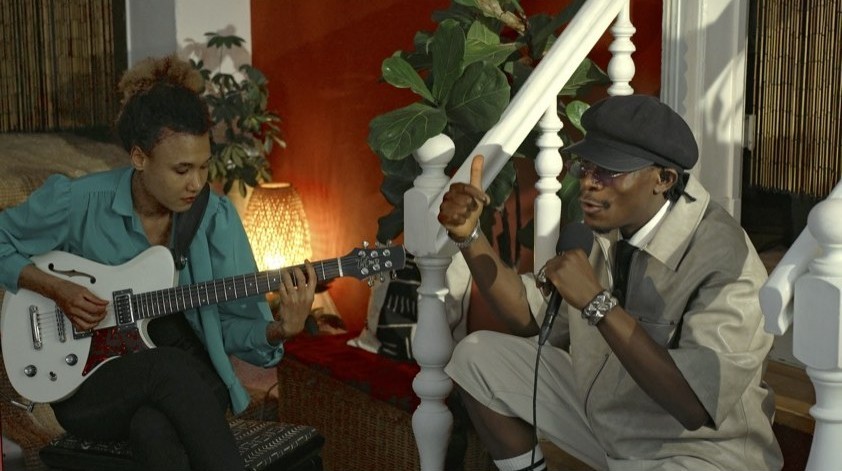DMC Reigns performing live with a guitarist in the living room set